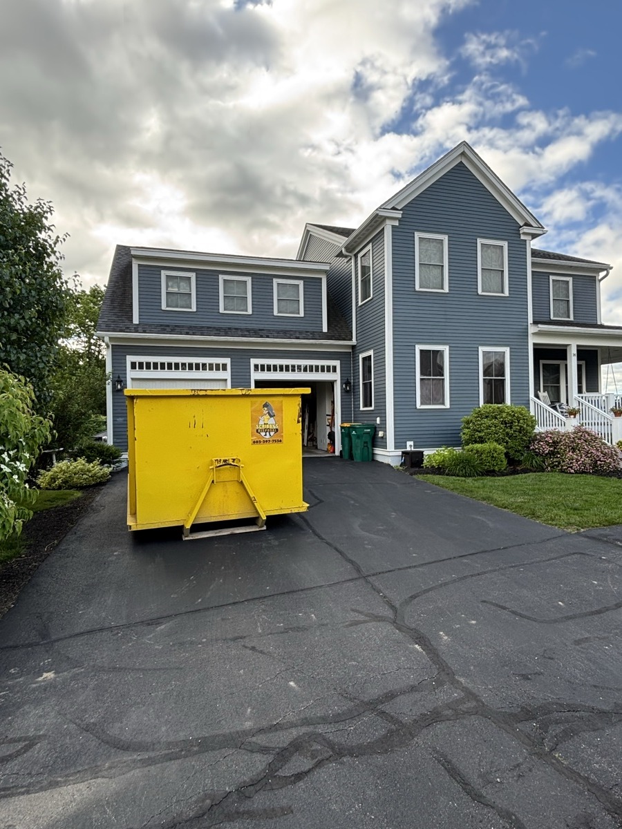 Yellow Scribby's 15-yard roll-off dumpster delivered to a freshly paved residential driveway in southern New Hampshire.