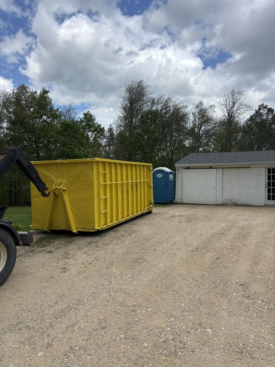 A Scribby's dumpster on a Northwood driveway. Maybe a residential cleanout in a rural neighborhood off Route 4, with woods in the background.