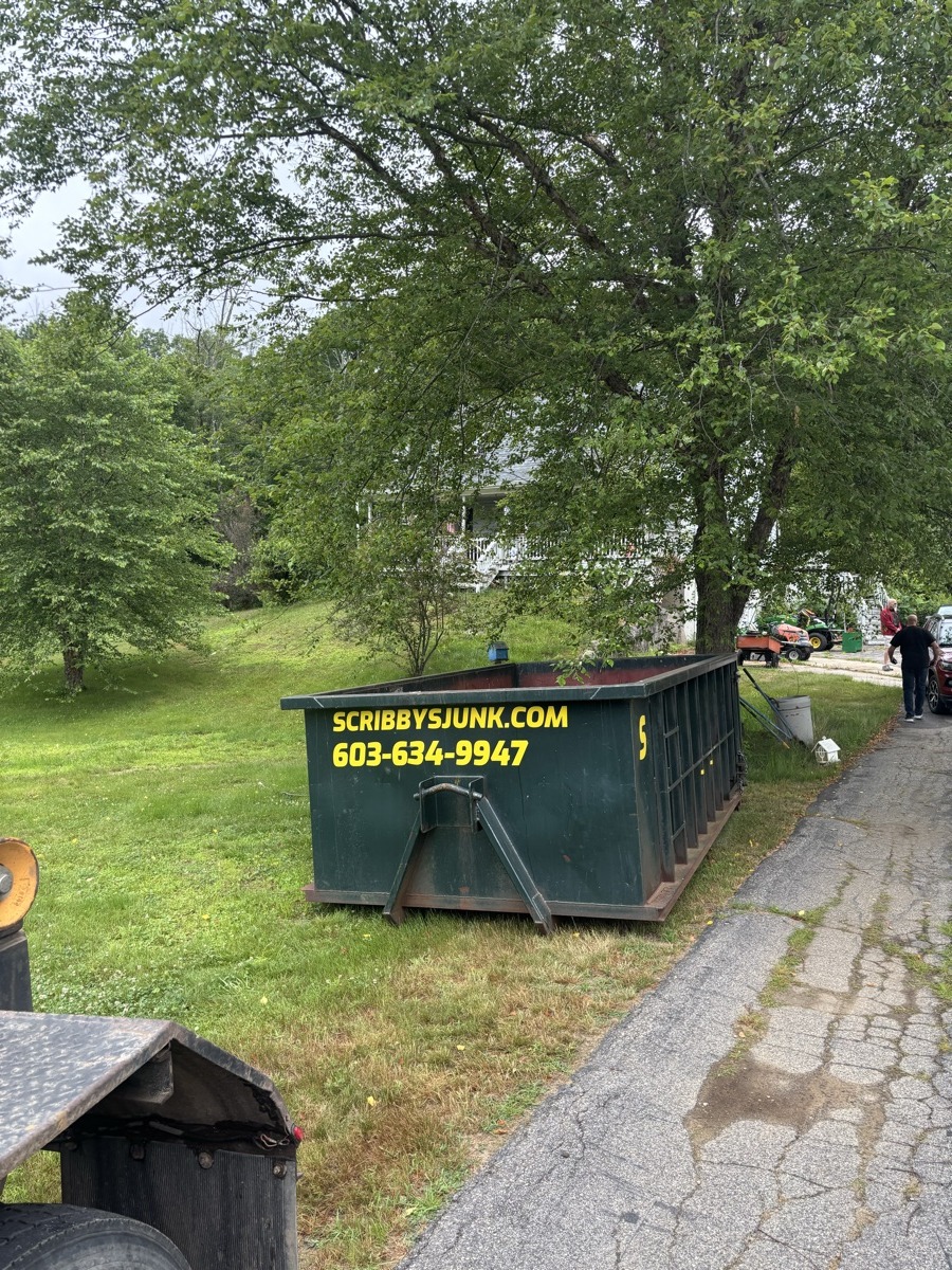 Yellow Scribby's roll-off dumpster placed on the lawn of a modest southern NH home, showing what on-grass placement looks like in practice.