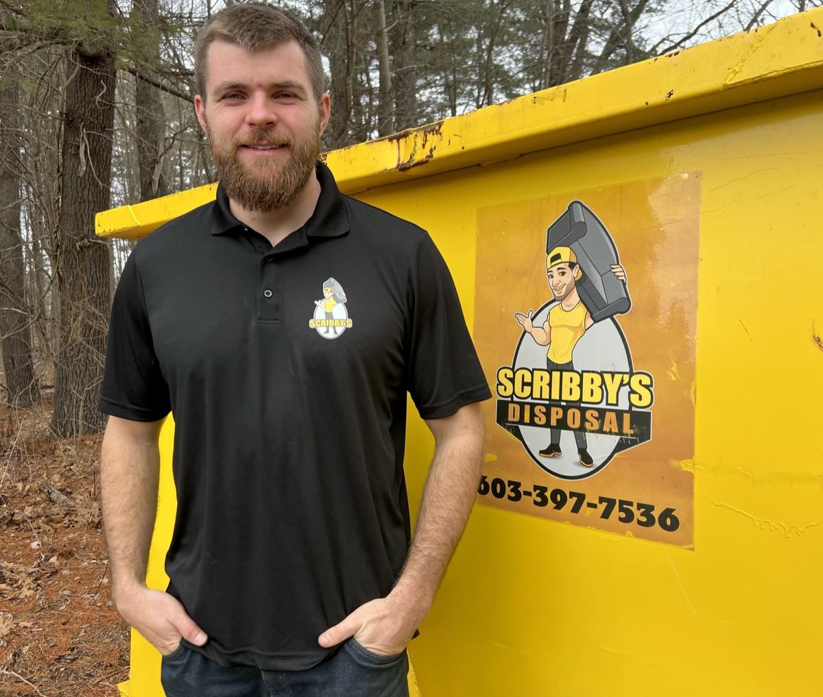 Declan, owner of Scribby's Dumpster Rentals, standing in front of a yellow Scribby's roll-off dumpster at the Fremont NH yard.